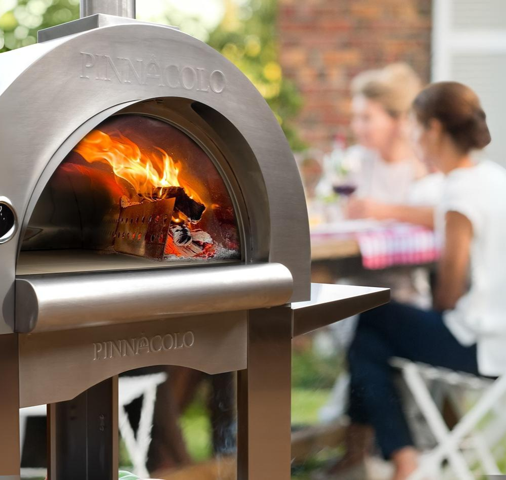 pizza oven with flame at front with people in the back